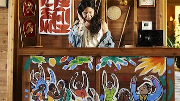 A wooden reception desk with a colorful mural depicting people celebrating.