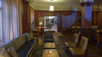 Een hotellobby met een bank, stoelen, een salontafel en een kroonluchter.