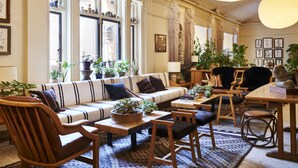 Un salon spacieux avec un canapé, des fauteuils, une table basse et des plantes en pot.