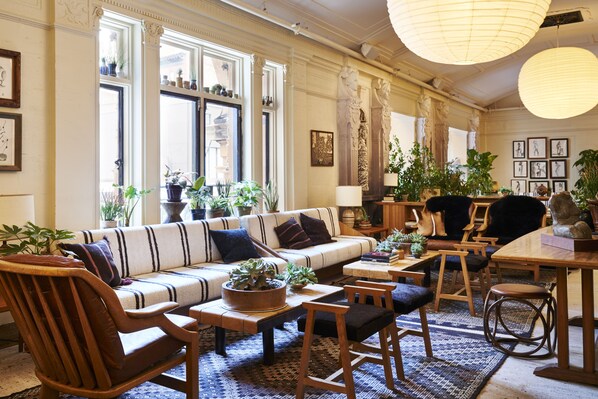 Uma sala de estar ampla com sofá, cadeiras, mesa de centro e plantas em vasos.
