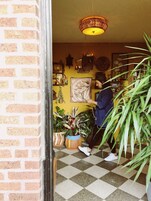 Una habitación con suelo a cuadros, lámpara colgante y varios adornos en la pared, incluyendo un cuadro enmarcado y un reloj.