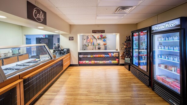 A café with a display case, a frozen food section, and a marketplace sign. - Holiday Inn Club Vacations Oak 'n Spruce Resort (South Lee)