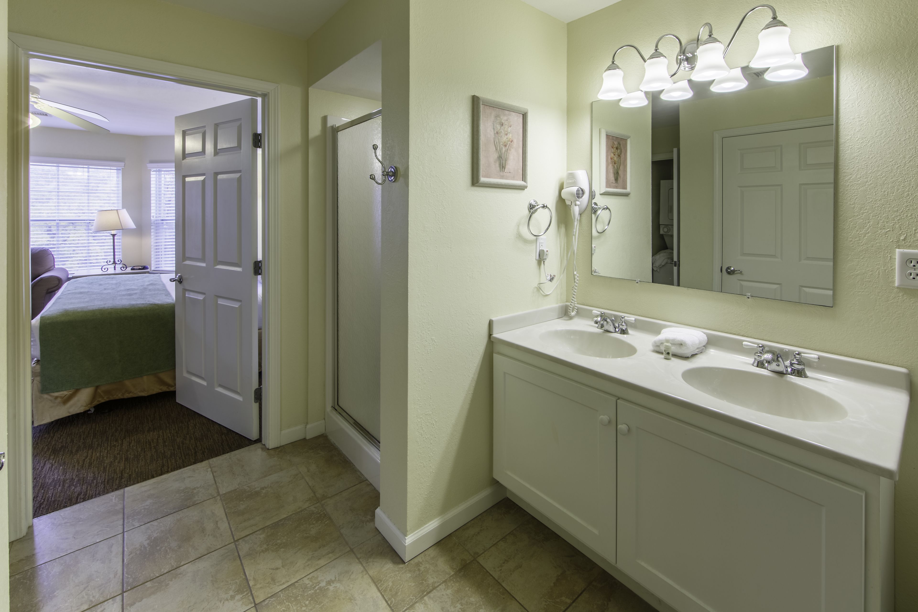 A bathroom with two sinks, a large mirror, and a hairdryer on the wall.