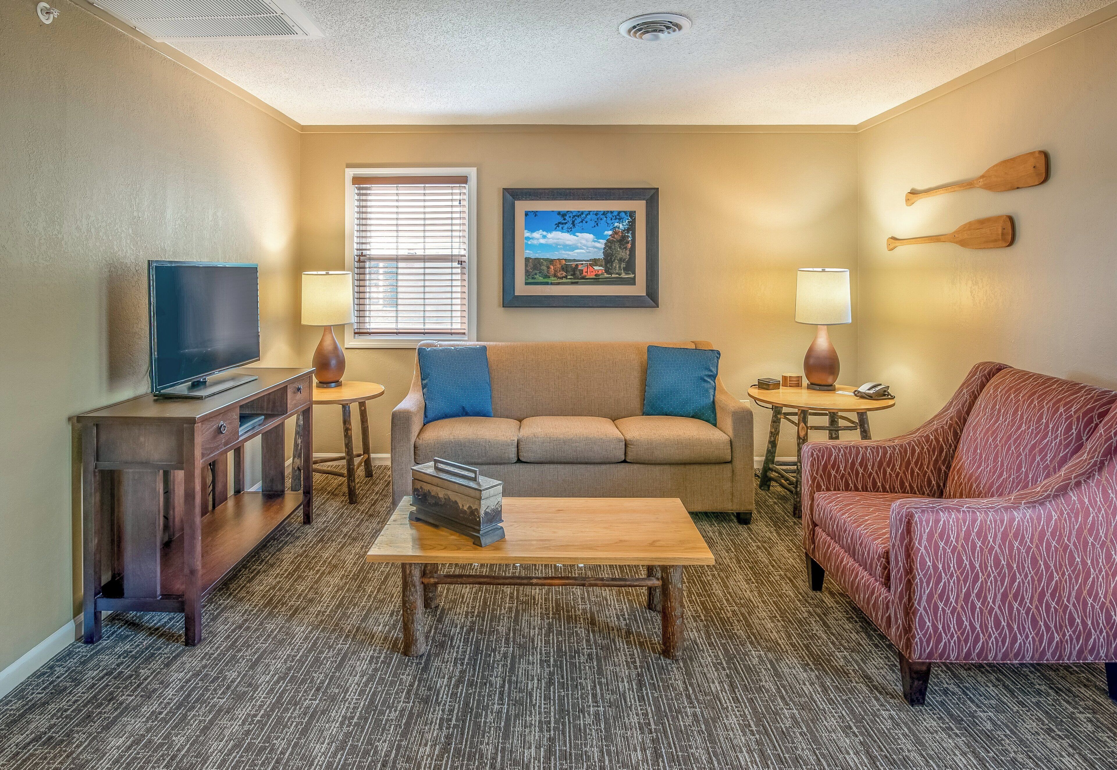 A living room with a television, sofa, coffee table, and two lamps.