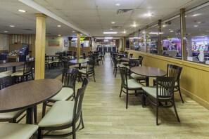 A spacious indoor dining area with multiple tables and chairs, a counter, and a visible pizza menu.