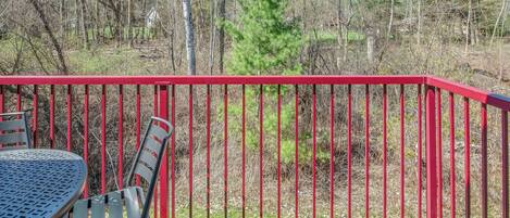 A deck with a red railing, a table, and a chair.