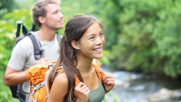 A person with an orange backpack standing in a lush green environment.