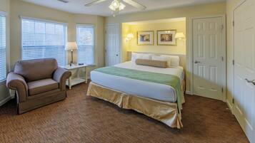 A bedroom with a bed, a chair, a desk, and a ceiling fan.