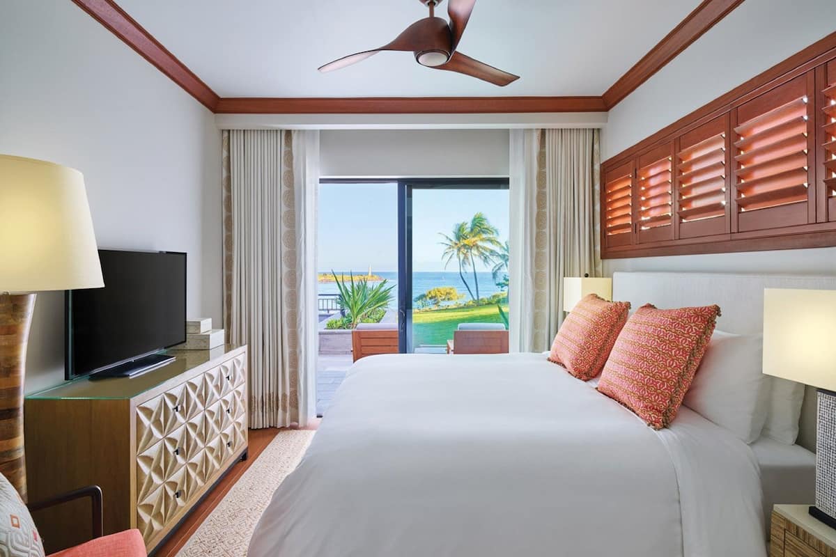 Une chambre d’hôtel avec un grand lit, un téléviseur posé sur un meuble et une vue sur l’océan.