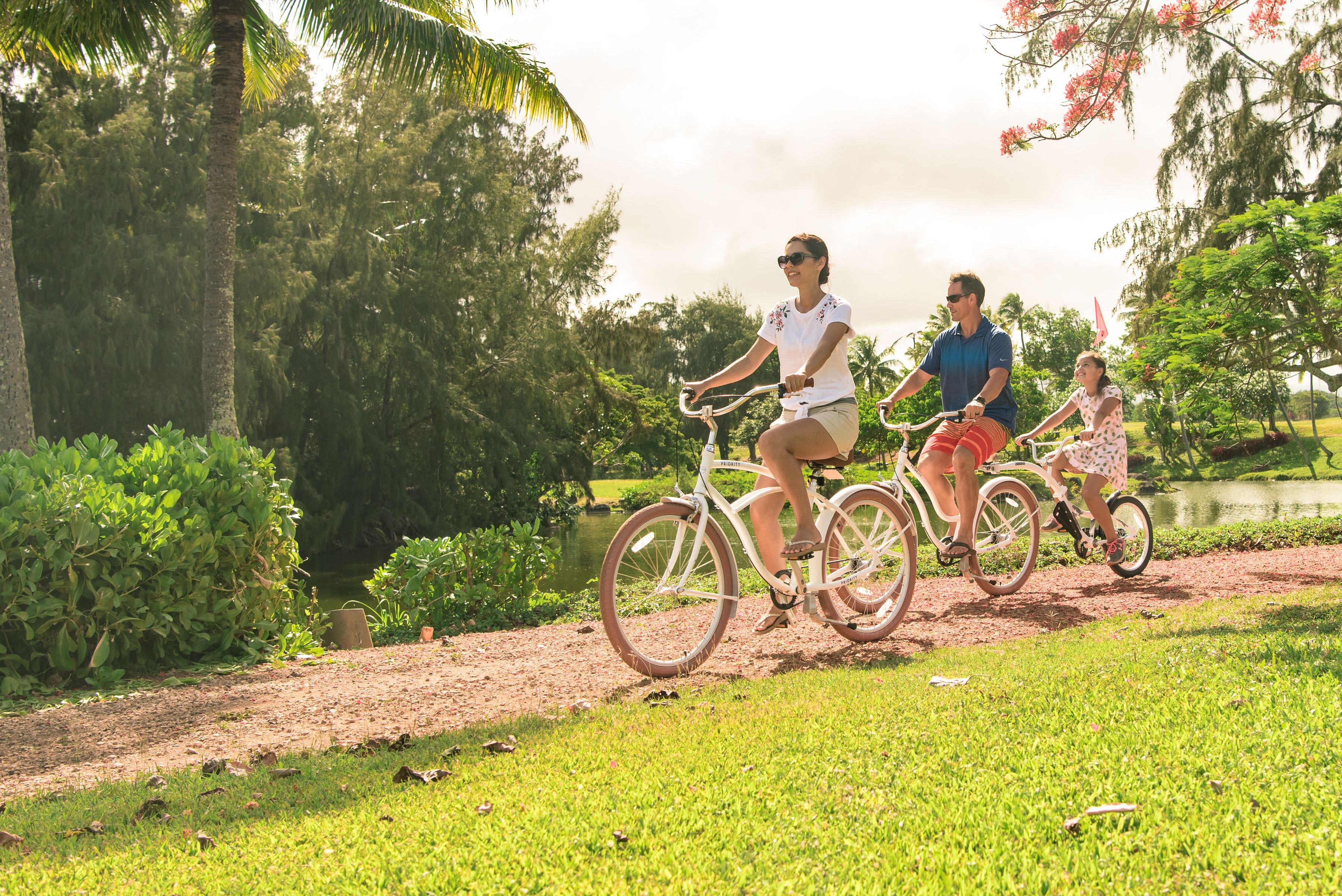 A pathway with three people riding bicycles, surrounded by greenery and trees.
