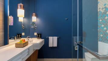 A modern bathroom with a blue wall, two sinks, a glass shower enclosure, and a towel rack.