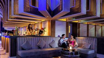 Un espace lounge moderne doté d’un bar, de sièges et de panneaux décoratifs au plafond.