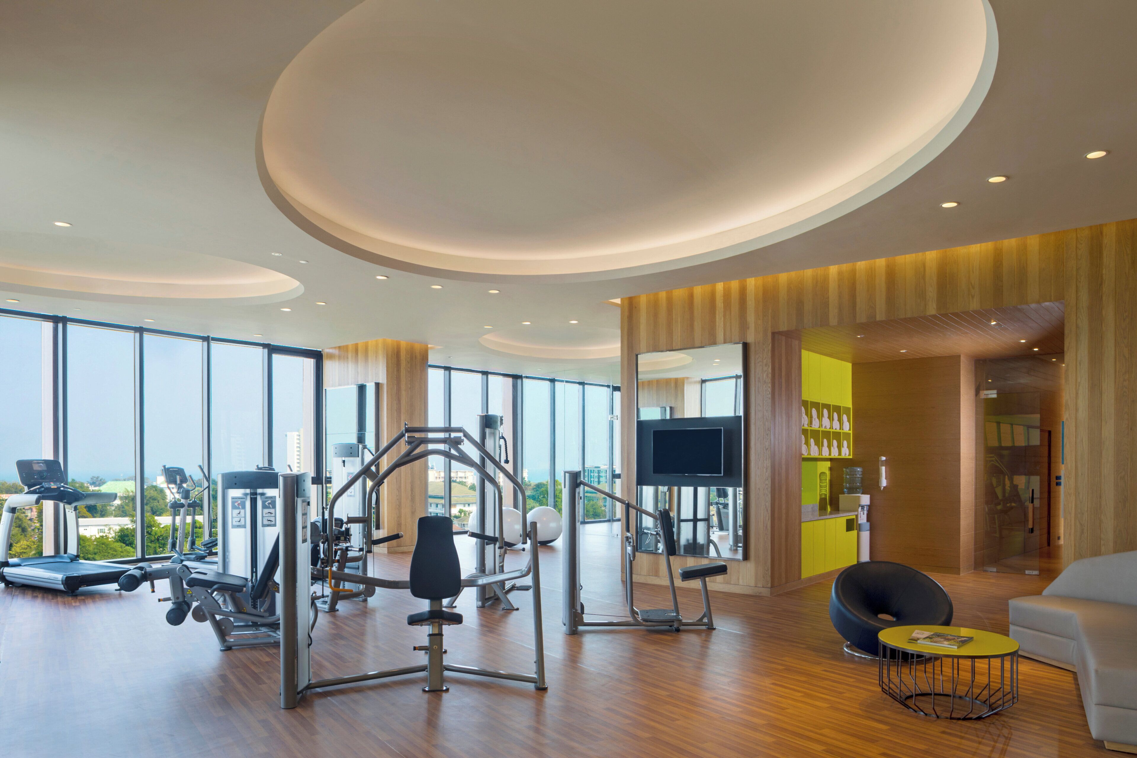 Un gimnasio moderno con equipo de ejercicio, un televisor y vistas a la ciudad.