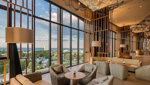 A spacious lounge with large windows offering a city view, comfortable seating, and modern decor.