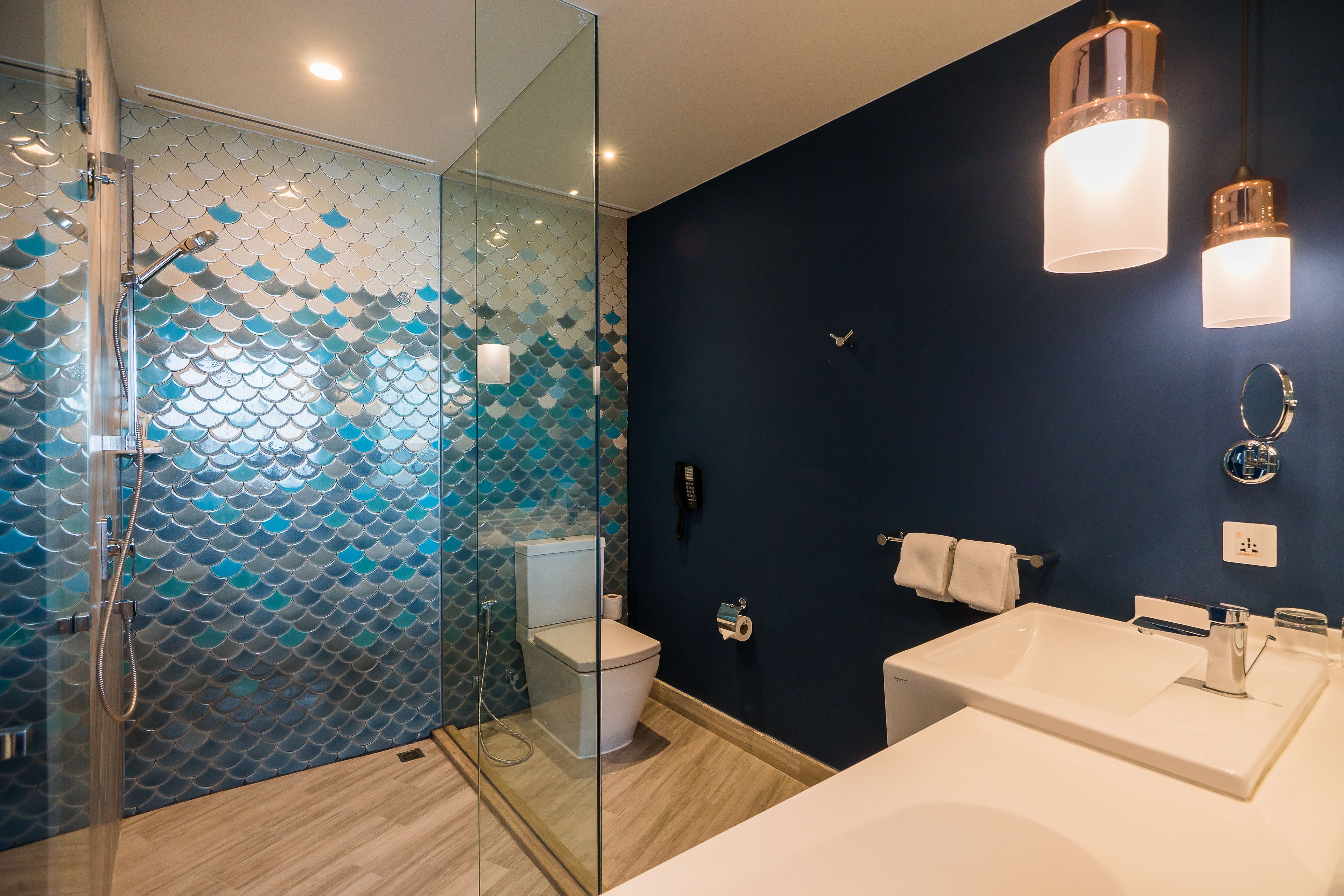 A modern bathroom with a glass-enclosed shower, a white sink, and a dark blue accent wall.