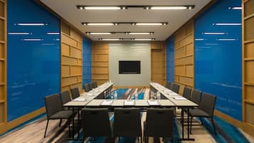 A conference room with a long table, chairs, and a flat-screen TV.