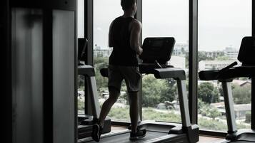 A gym with treadmills and a large window offering a view of the city.