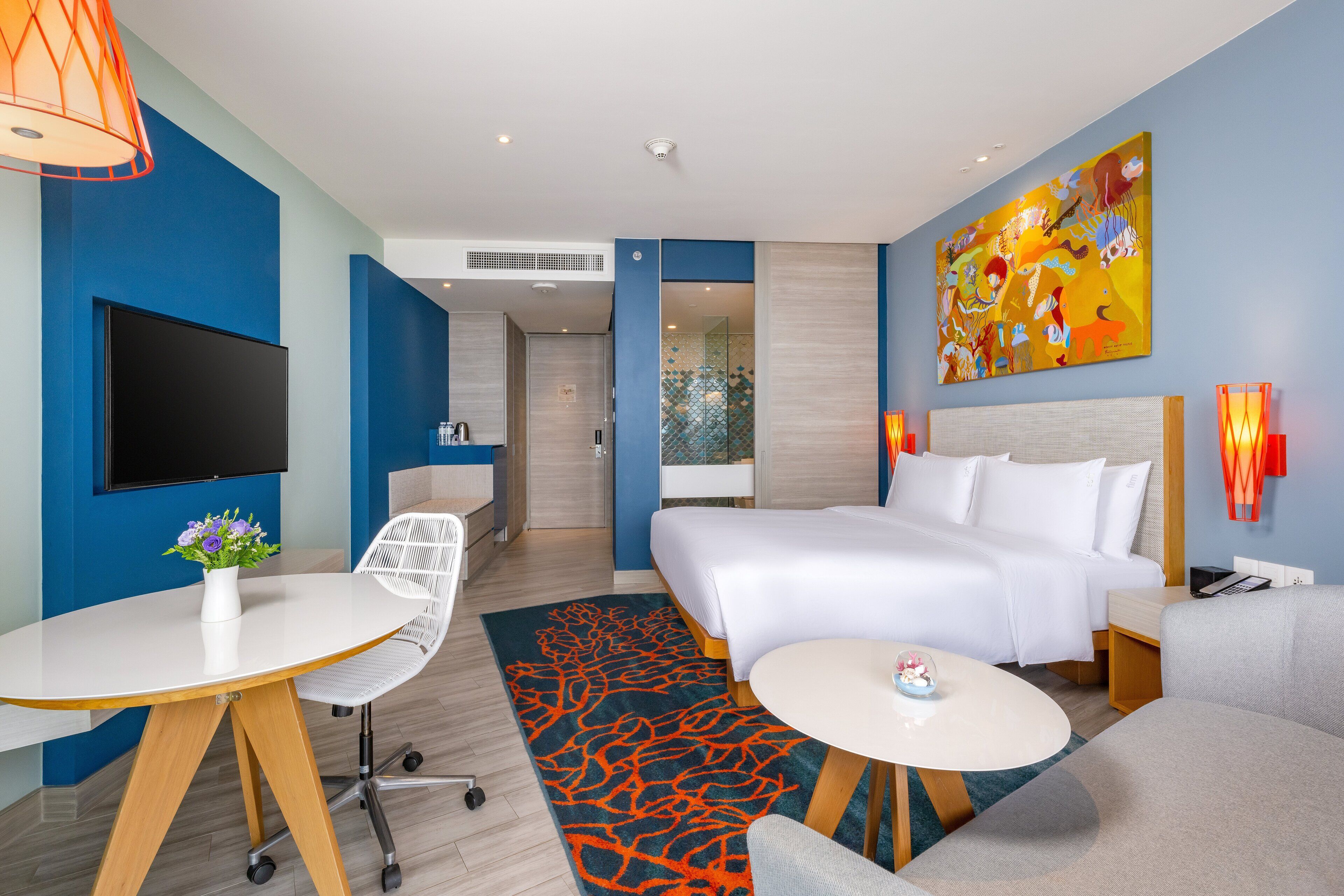 Une chambre d’hôtel moderne avec un grand lit, un bureau, une télévision et un tableau au mur.