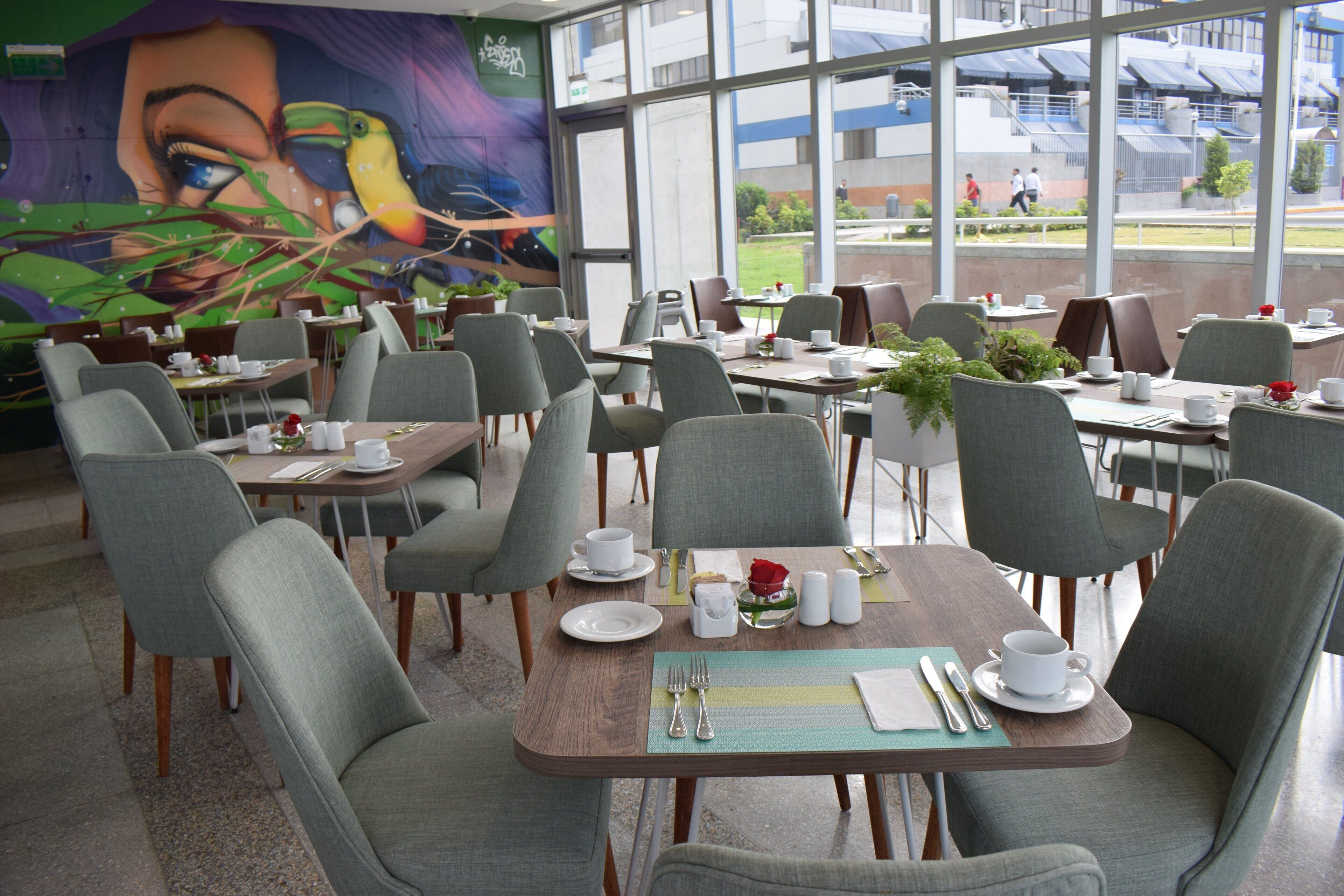 Un restaurant doté de nombreuses tables et chaises, dont certaines sont dressées avec la vaisselle nécessaire.