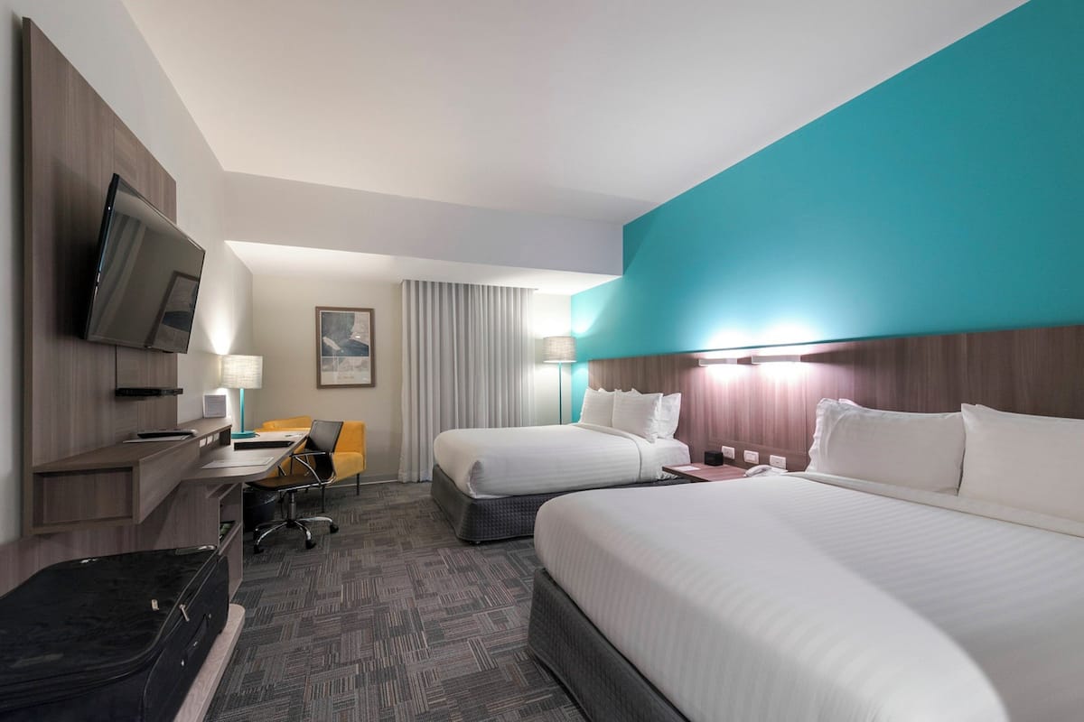 A hotel room with a bed, desk, chair, and a television.