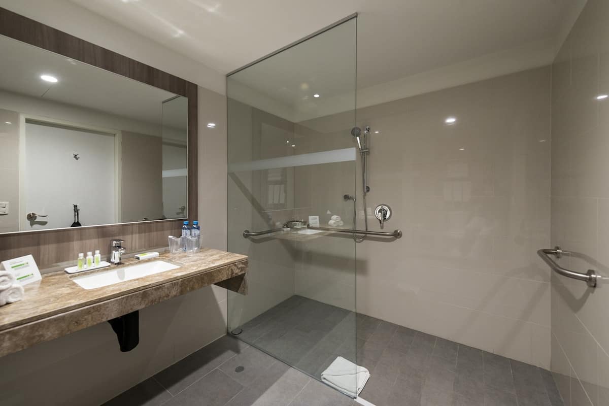A modern bathroom with a glass-enclosed shower, a marble sink, and a large mirror.