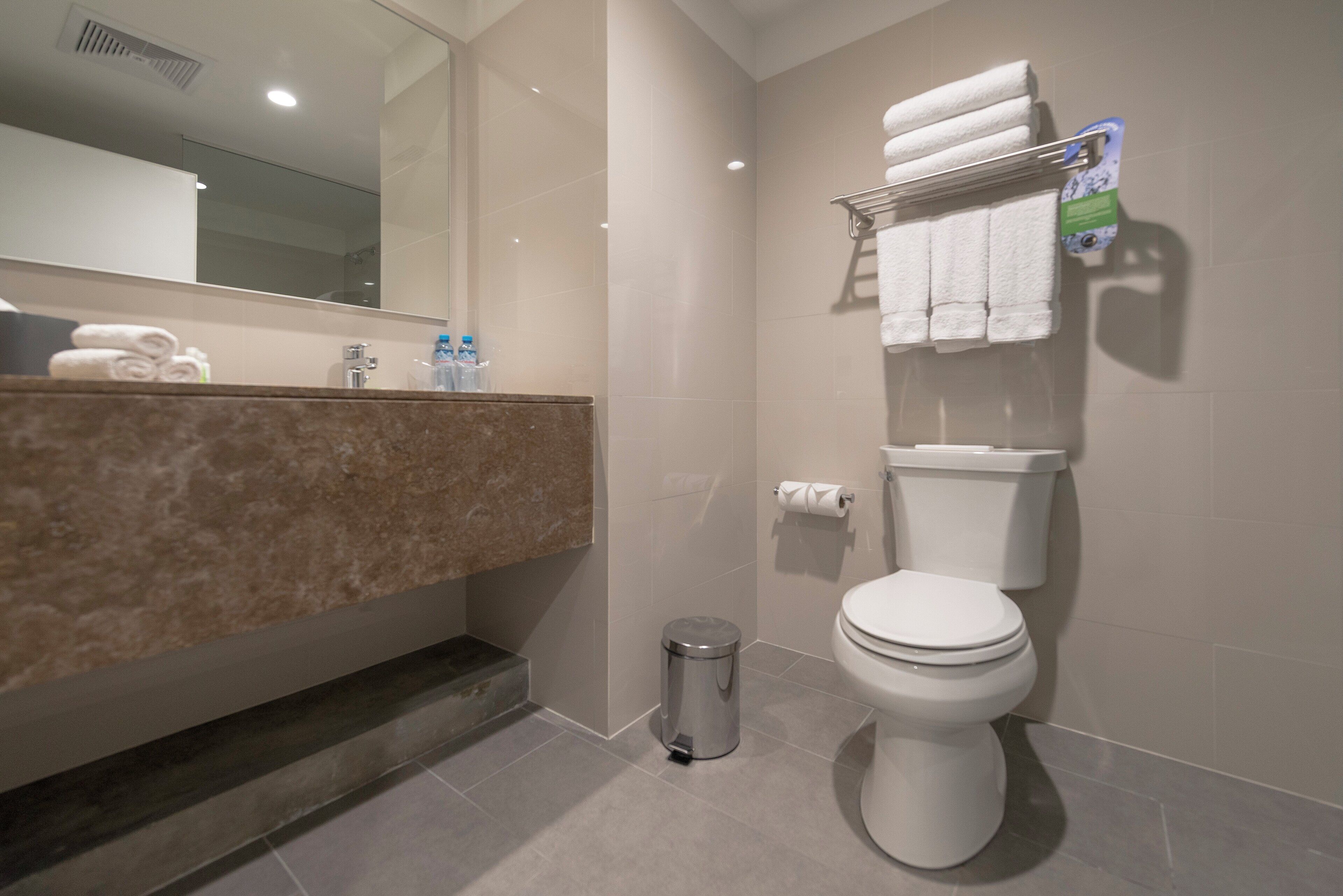 A modern bathroom with a toilet, sink, and mirror.