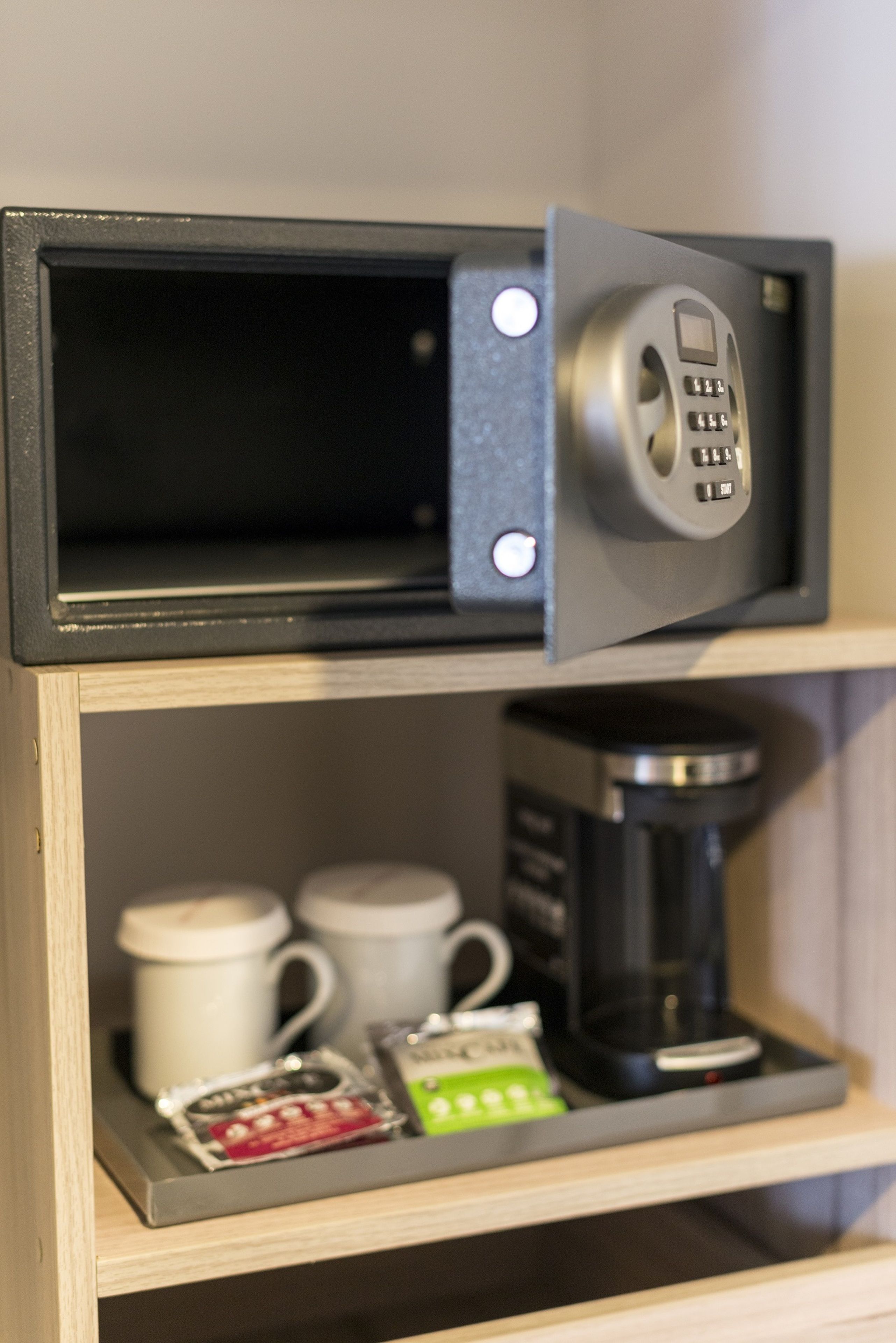 Een koffieapparaat en twee mokken op een plank.