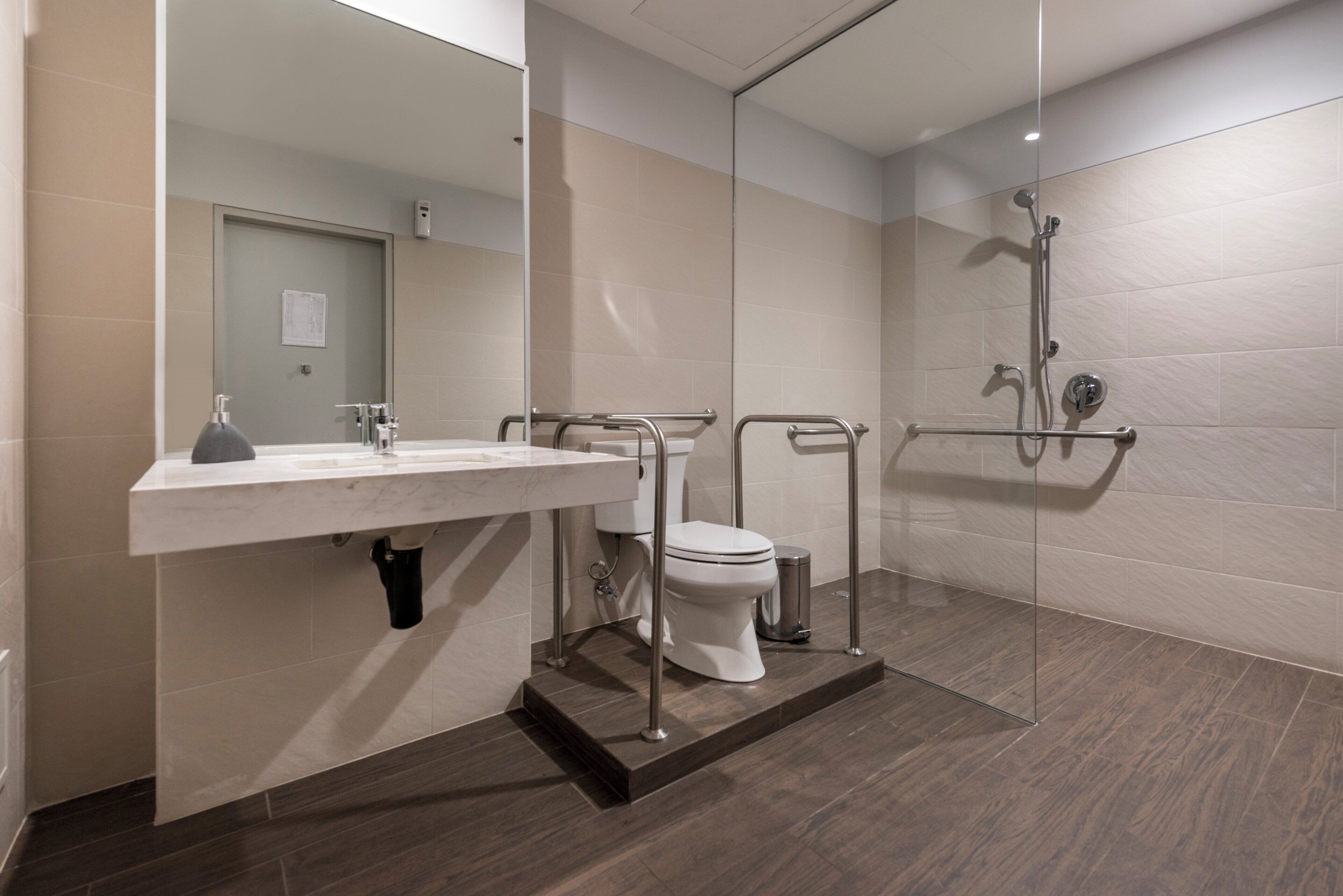 Un baño moderno con lavamanos, inodoro y zona de ducha blancos.