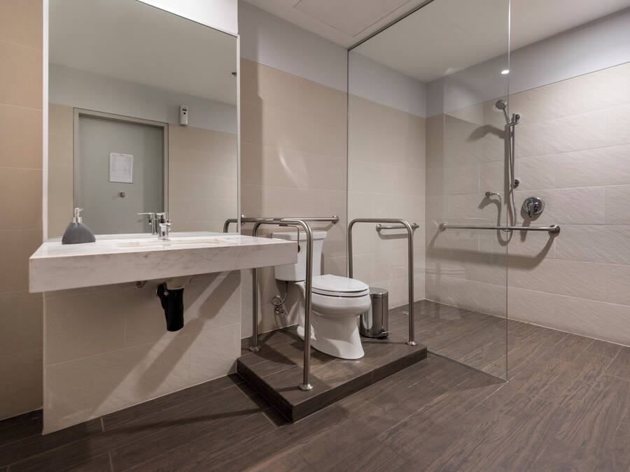 Un baño moderno con lavamanos, inodoro y zona de ducha blancos.