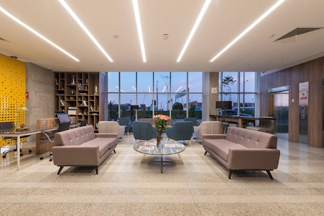 A modern lobby with seating, a coffee table, and a bookshelf.