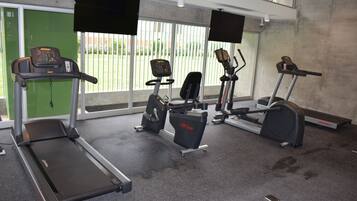 Une salle de sport équipée de tapis de course, de vélos d’appartement et d’un appareil d’aviron.