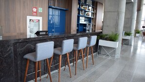 A bar area with a marble counter, four grey bar stools, and a blue door. - Holiday Inn Lima Airport by IHG (Callao)
