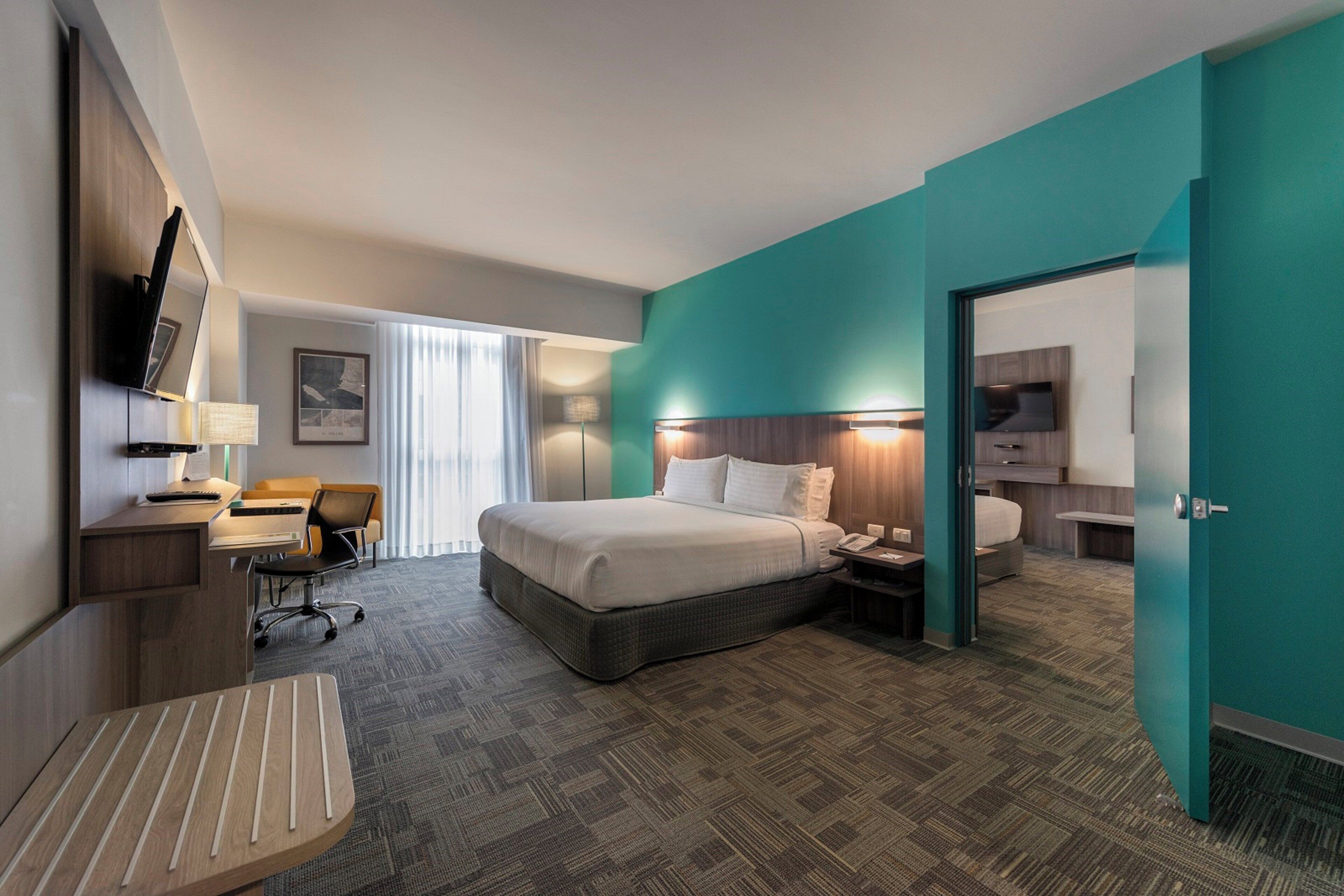 Una habitación de hotel con cama, escritorio, silla y televisor.
