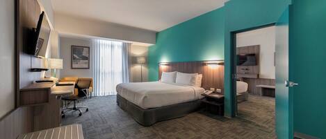 Una habitación de hotel con cama, escritorio, silla y televisor.