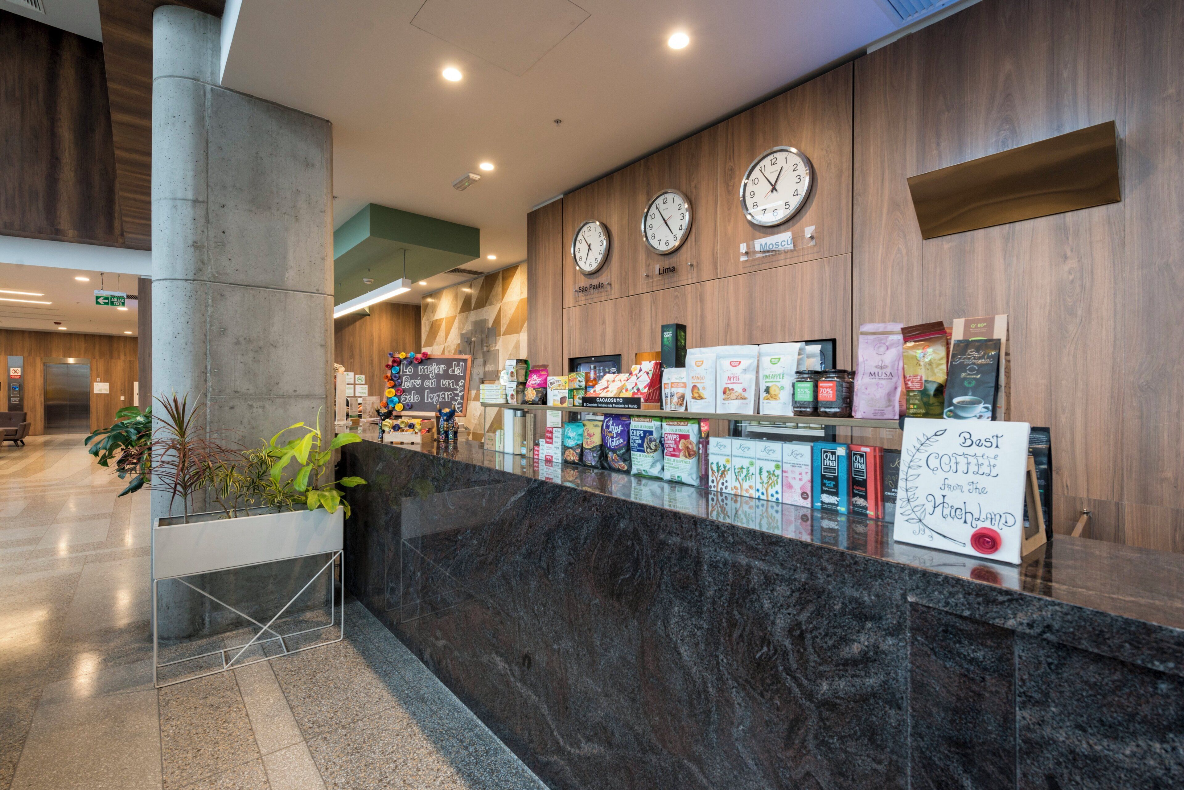 A reception area with a marble counter, clocks, and various snack and coffee products.