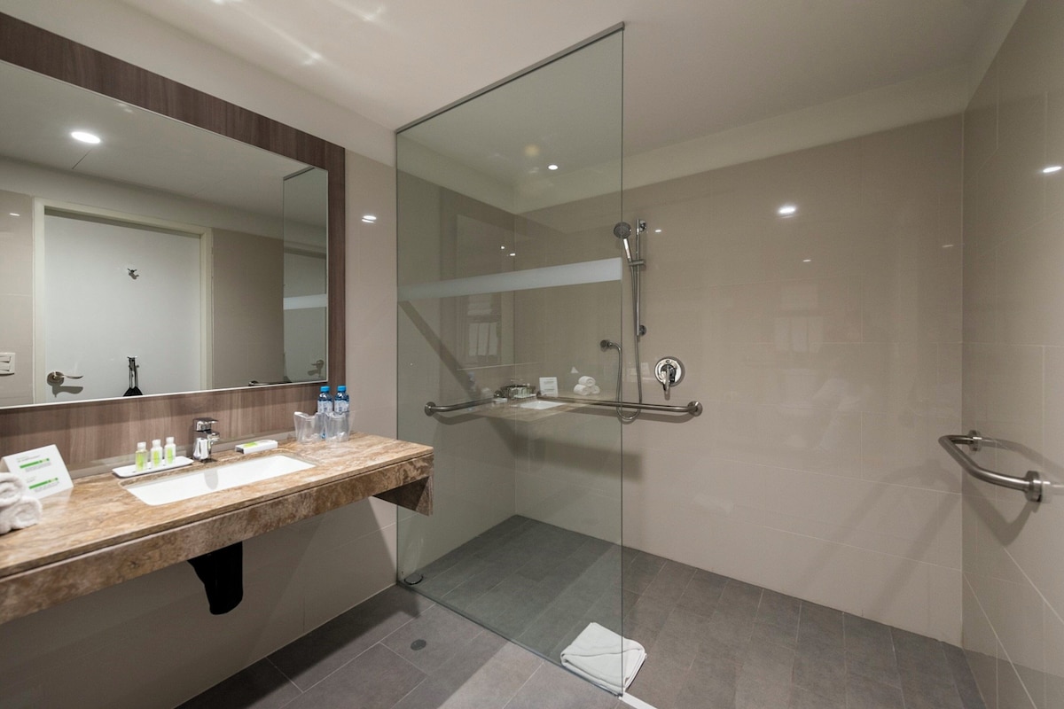A modern bathroom with a glass-enclosed shower, a marble sink, and a large mirror.