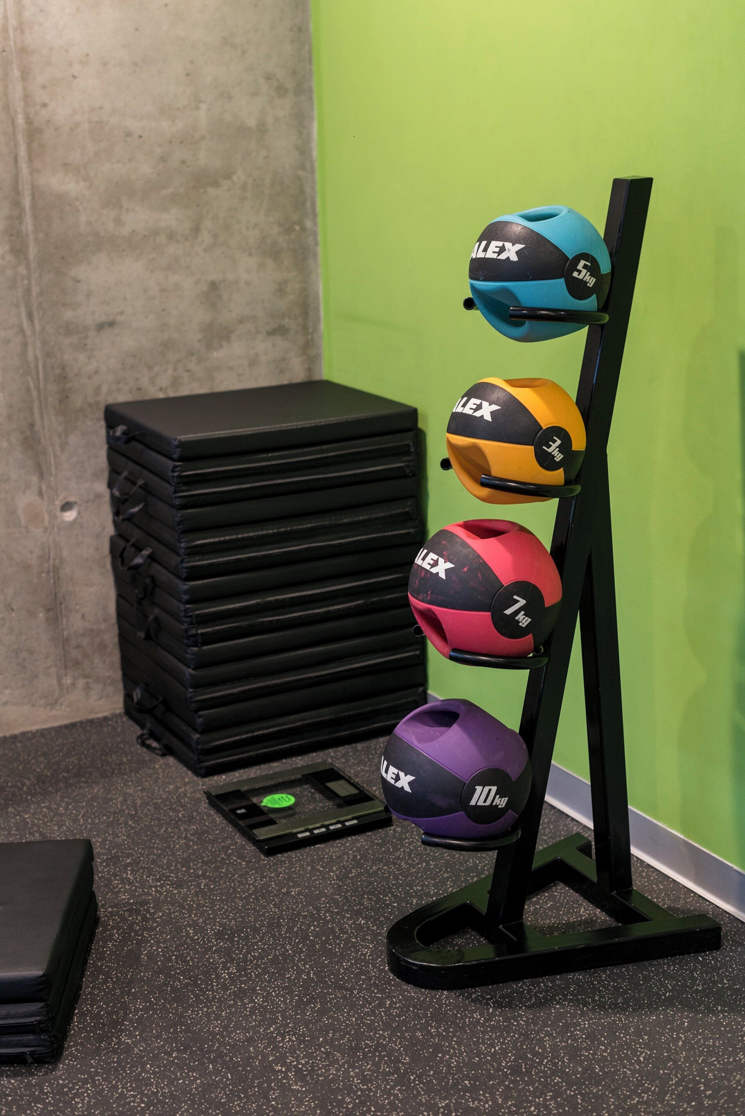 A weightlifting rack with various weights and a stack of black boxes.