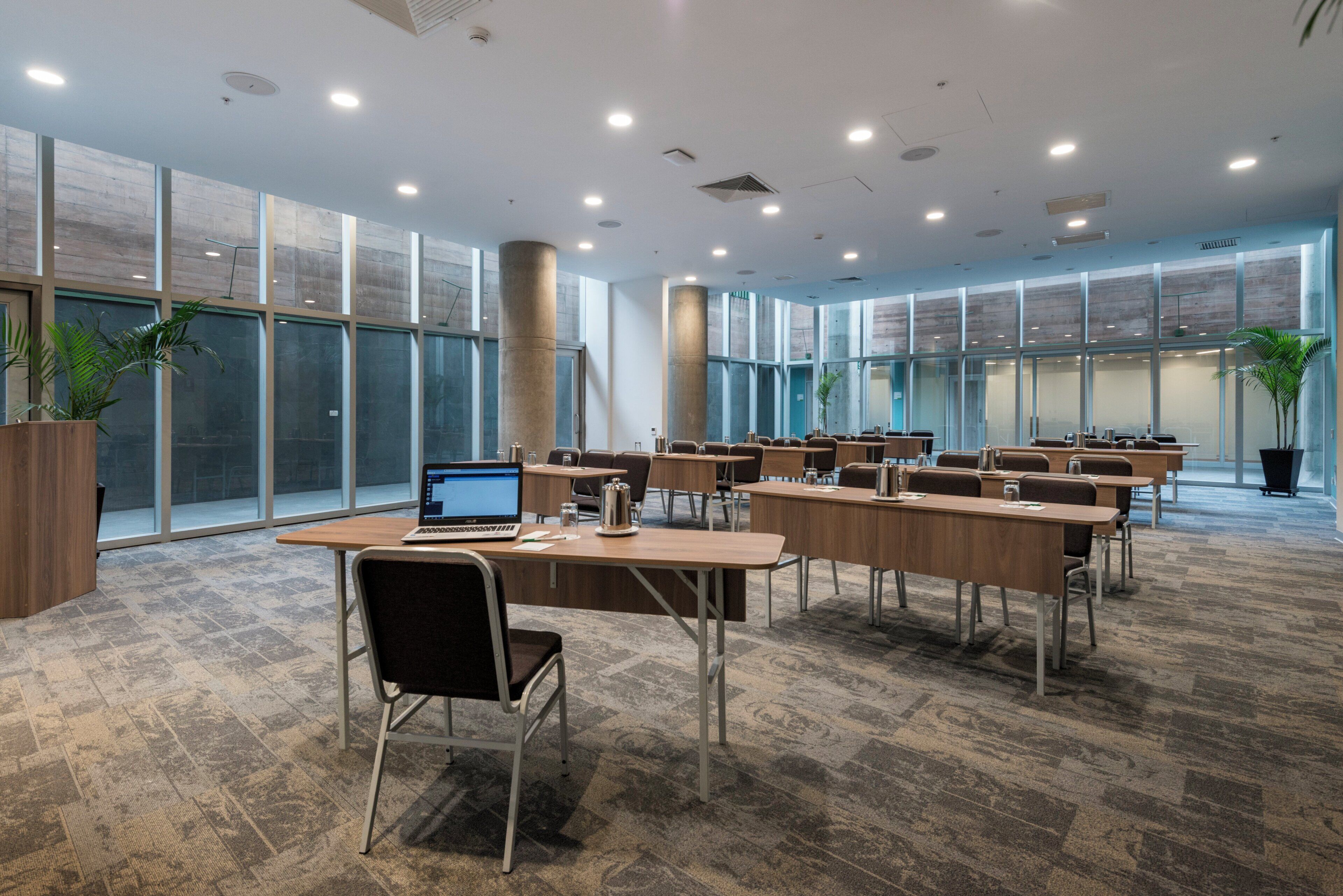 A conference room with multiple tables, chairs, and a laptop on one table.