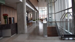 A modern lobby with a reception desk, seating area, and a staircase leading to upper floors.