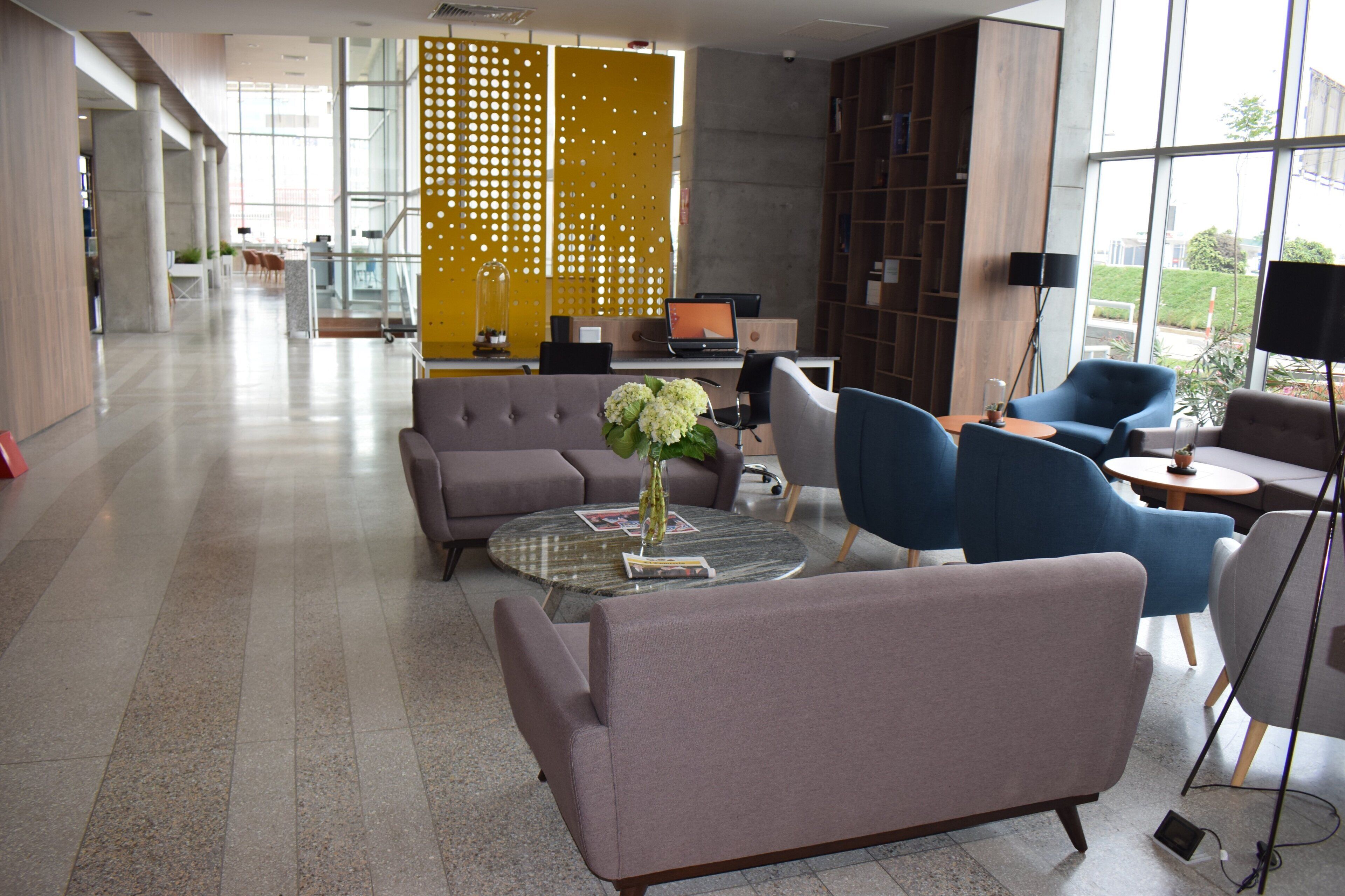 Ein moderner Lounge-Bereich mit Sitzgelegenheiten, einem Couchtisch und einem Laptop auf einem Schreibtisch.