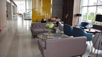 Ein moderner Lounge-Bereich mit Sitzgelegenheiten, einem Couchtisch und einem Laptop auf einem Schreibtisch.