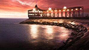A waterfront building with a glass facade, a central tower, and a series of lights along the roofline. - Holiday Inn Lima Airport by IHG (Callao)