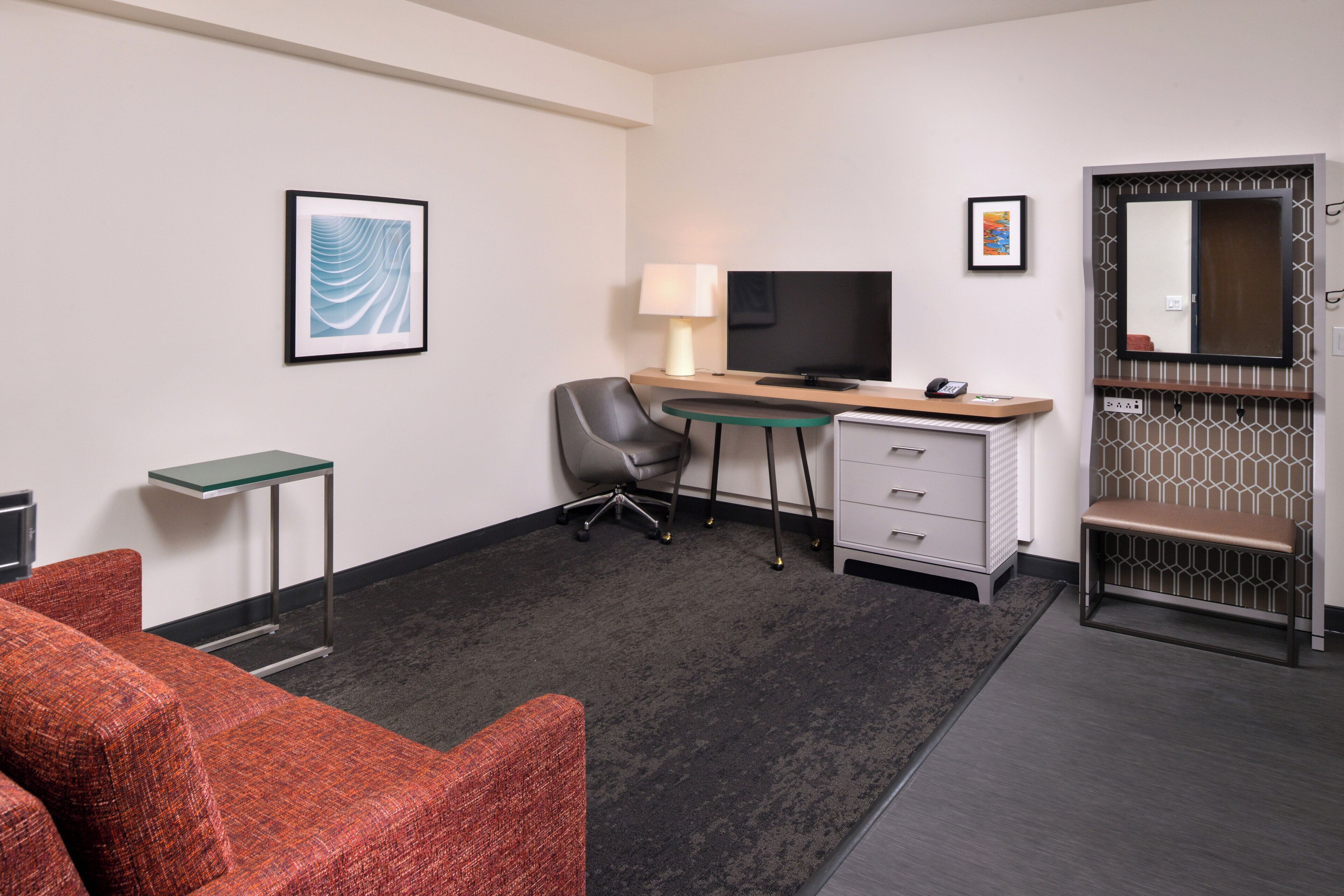 A hotel room with a desk, chair, television, and a bed.