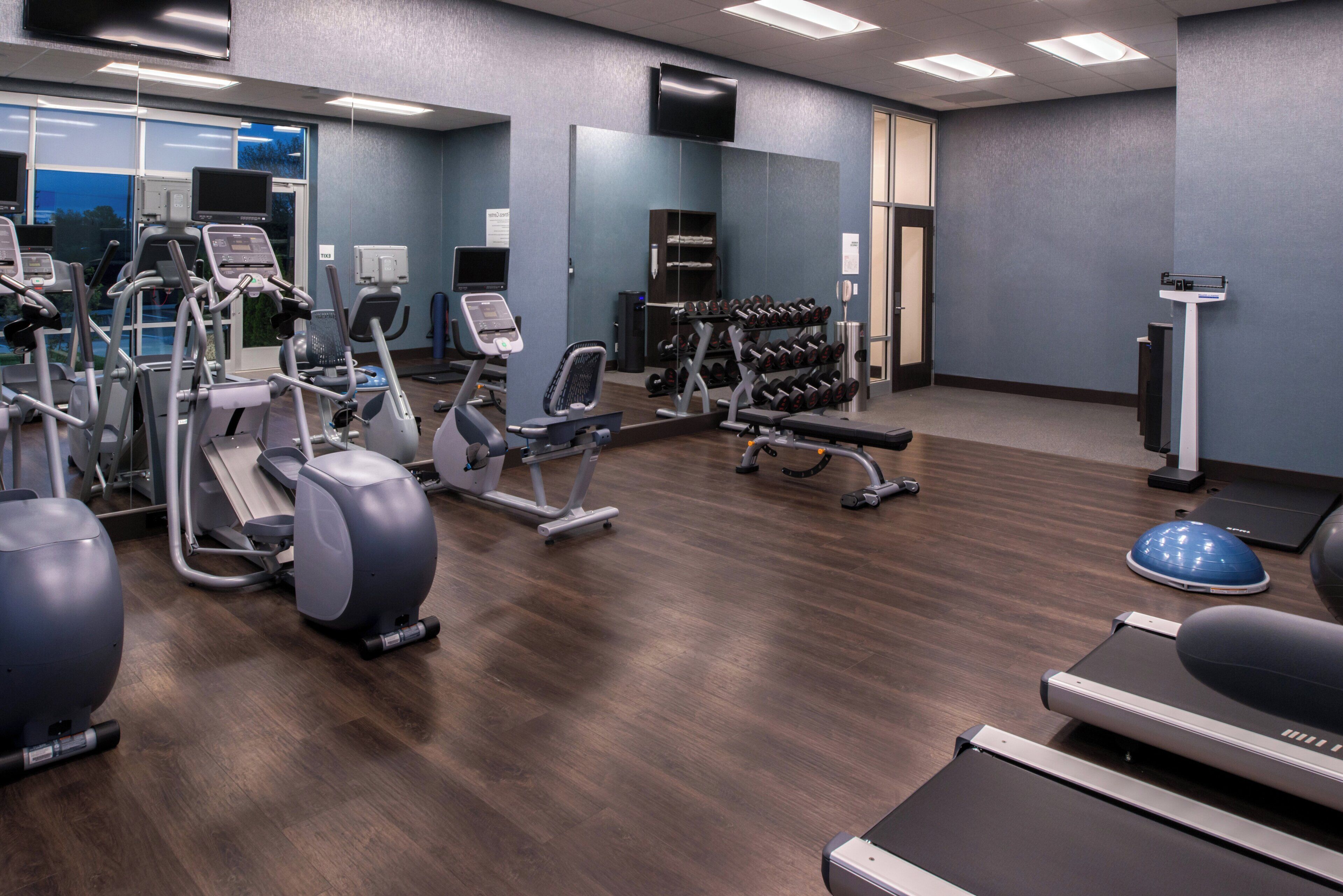A gym with various exercise equipment, including treadmills, elliptical machines, and free weights.