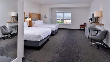 Une chambre d’hôtel avec deux lits, un bureau, une chaise, une fenêtre et une vue sur la ville.