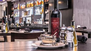 A bar area with a bottle of MARRAMIERO Inferi 2014, salt and pepper shakers, and a small dish on a table.