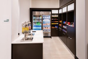Een moderne hotellobby met een automaat voor zelfbedieningdranken, een gekoeld display en een verkoopautomaat.