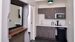 A compact kitchenette with a microwave, sink, and storage cabinets.