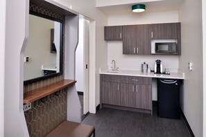 A compact kitchenette with a microwave, sink, and storage cabinets.