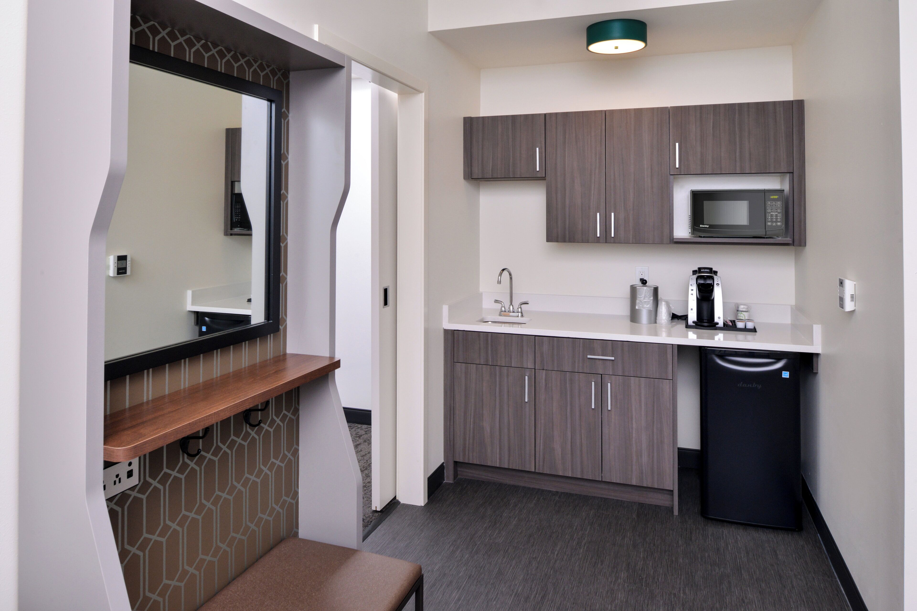A compact kitchenette with a microwave, sink, and a built-in dishwasher.